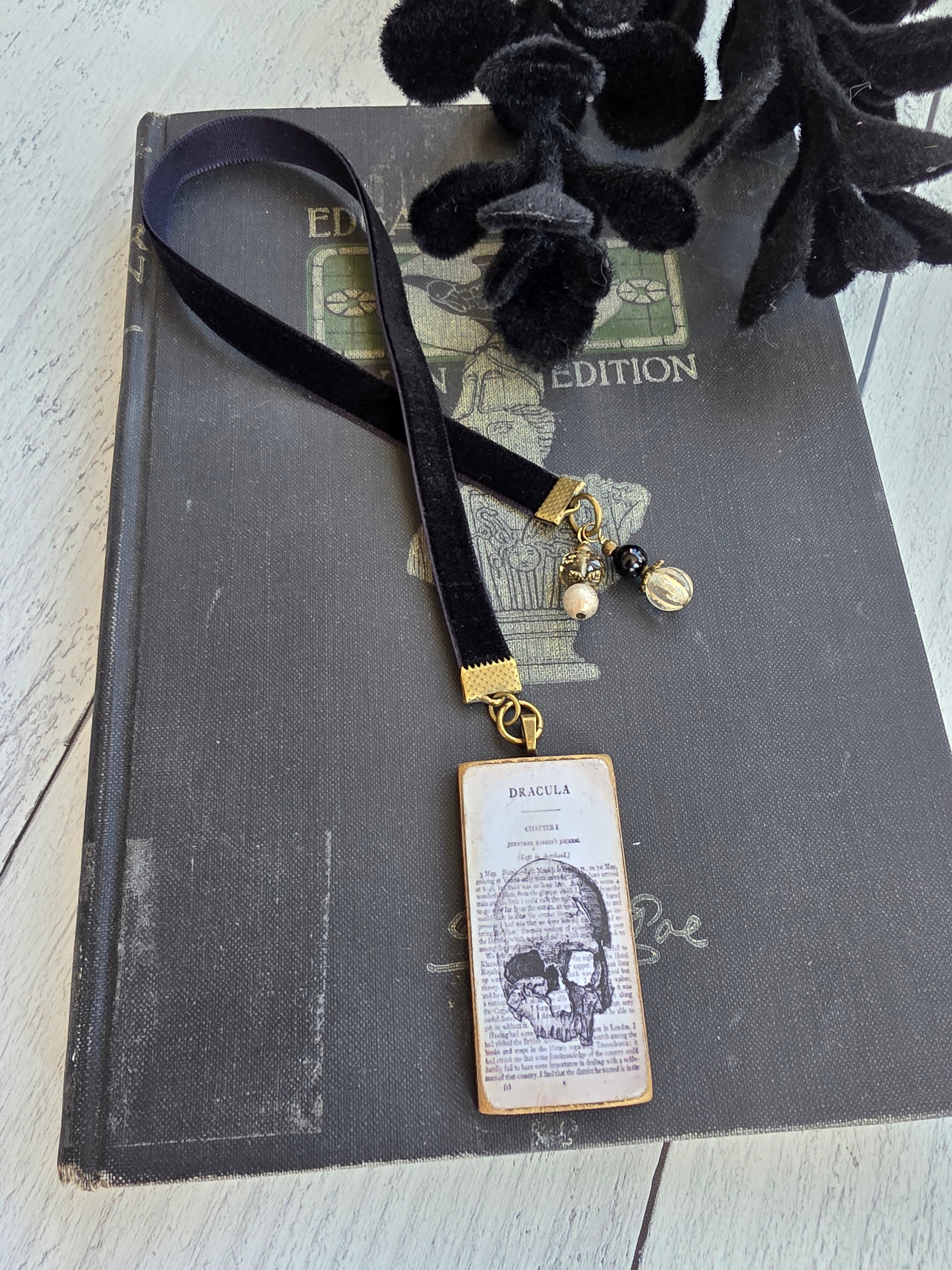 a black book with a bookmark shaped like a skull and a black velvet bookmark attached to it.