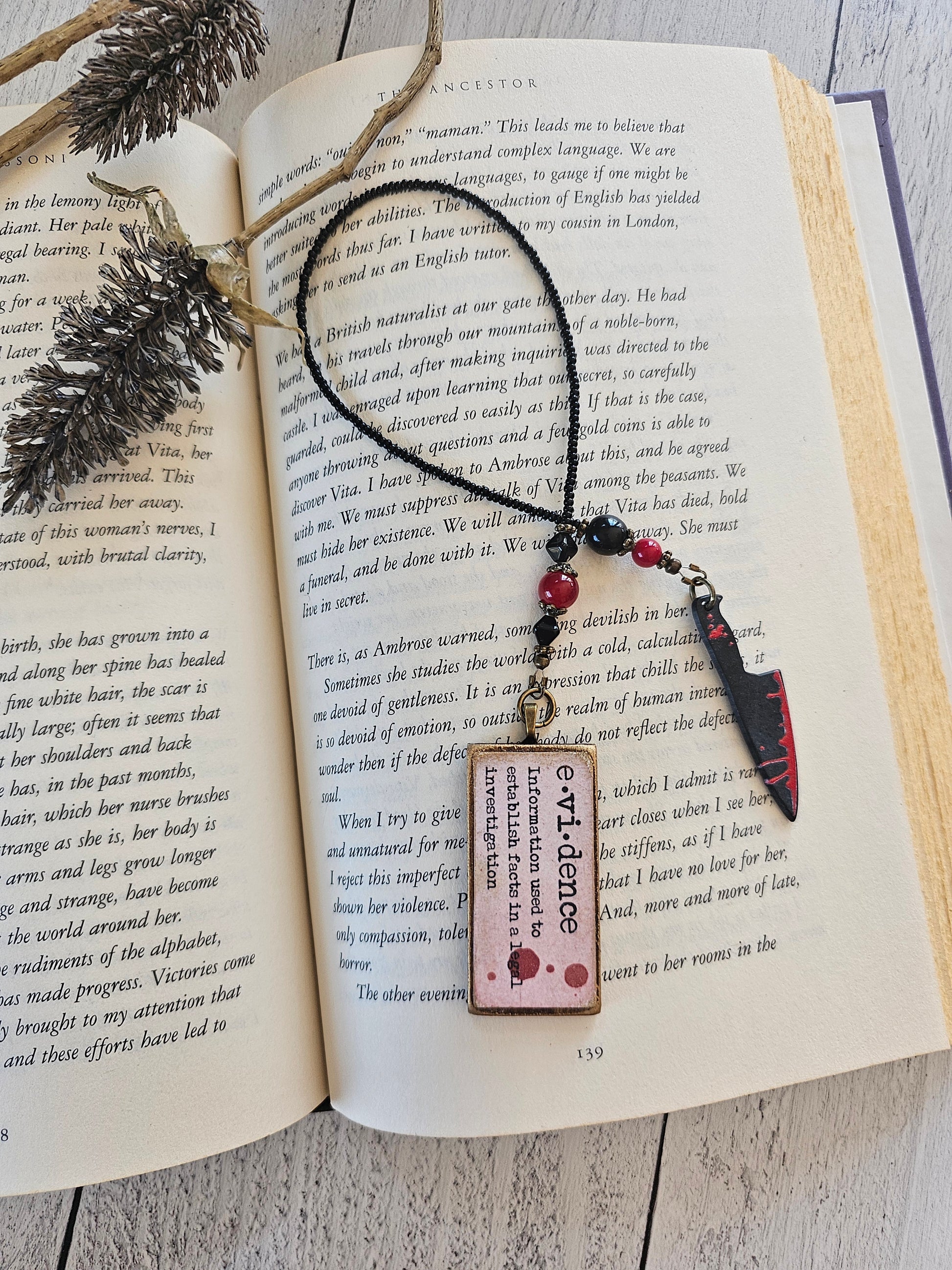 an open book with a bookmark shaped like a knife resting on top of the pages.