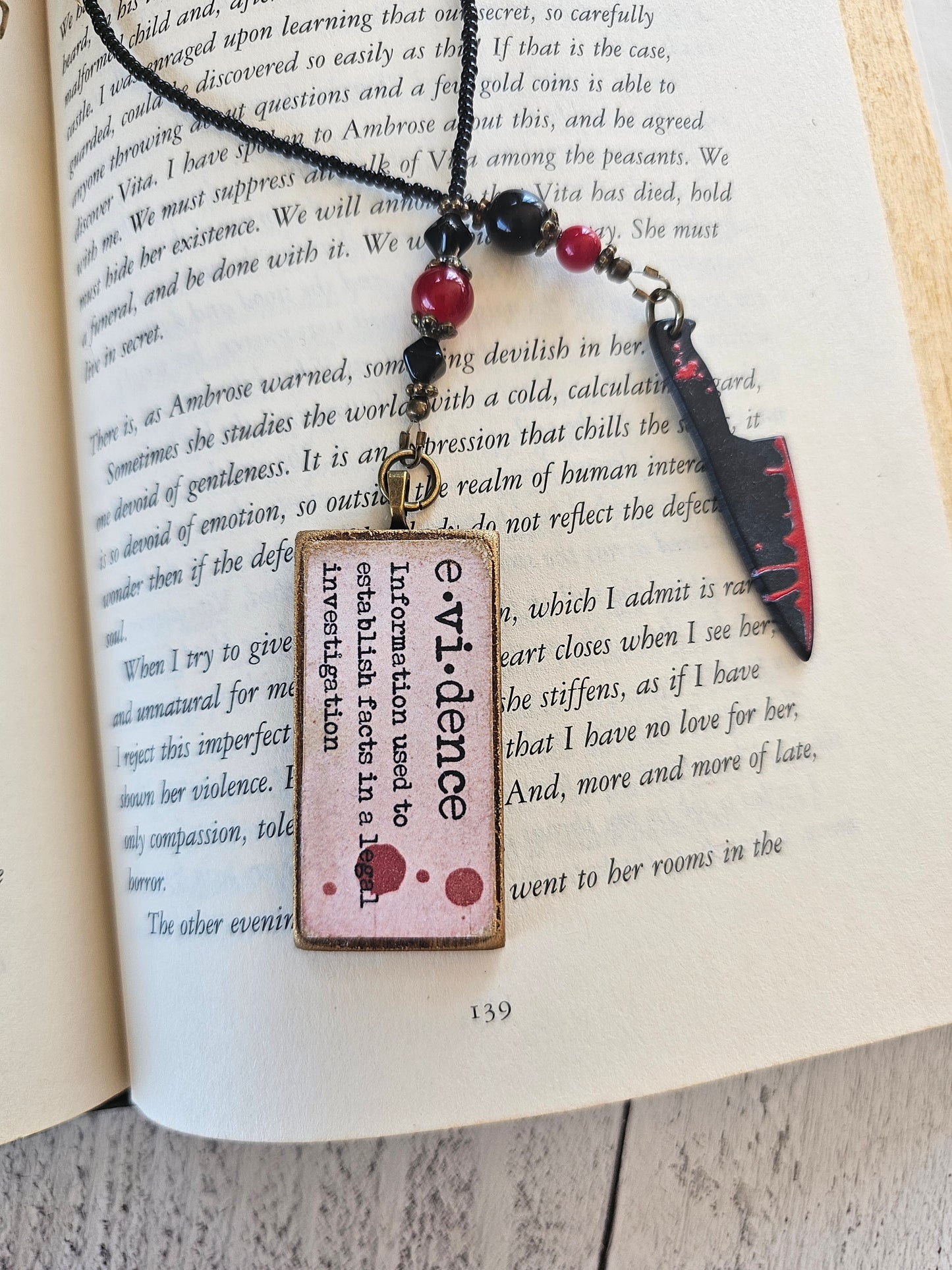 a knife with a red and black blade lying on top of an open book with text on the pages.
