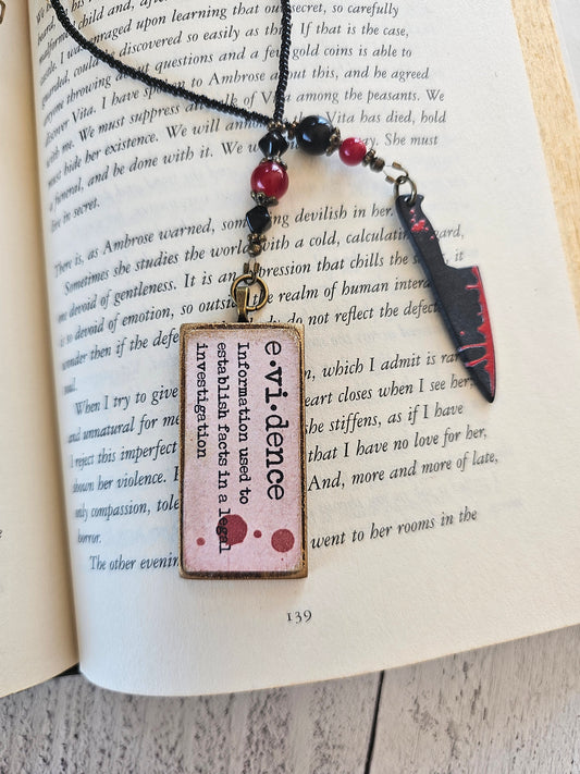 a knife with a red and black blade lying on top of an open book with text on the pages.