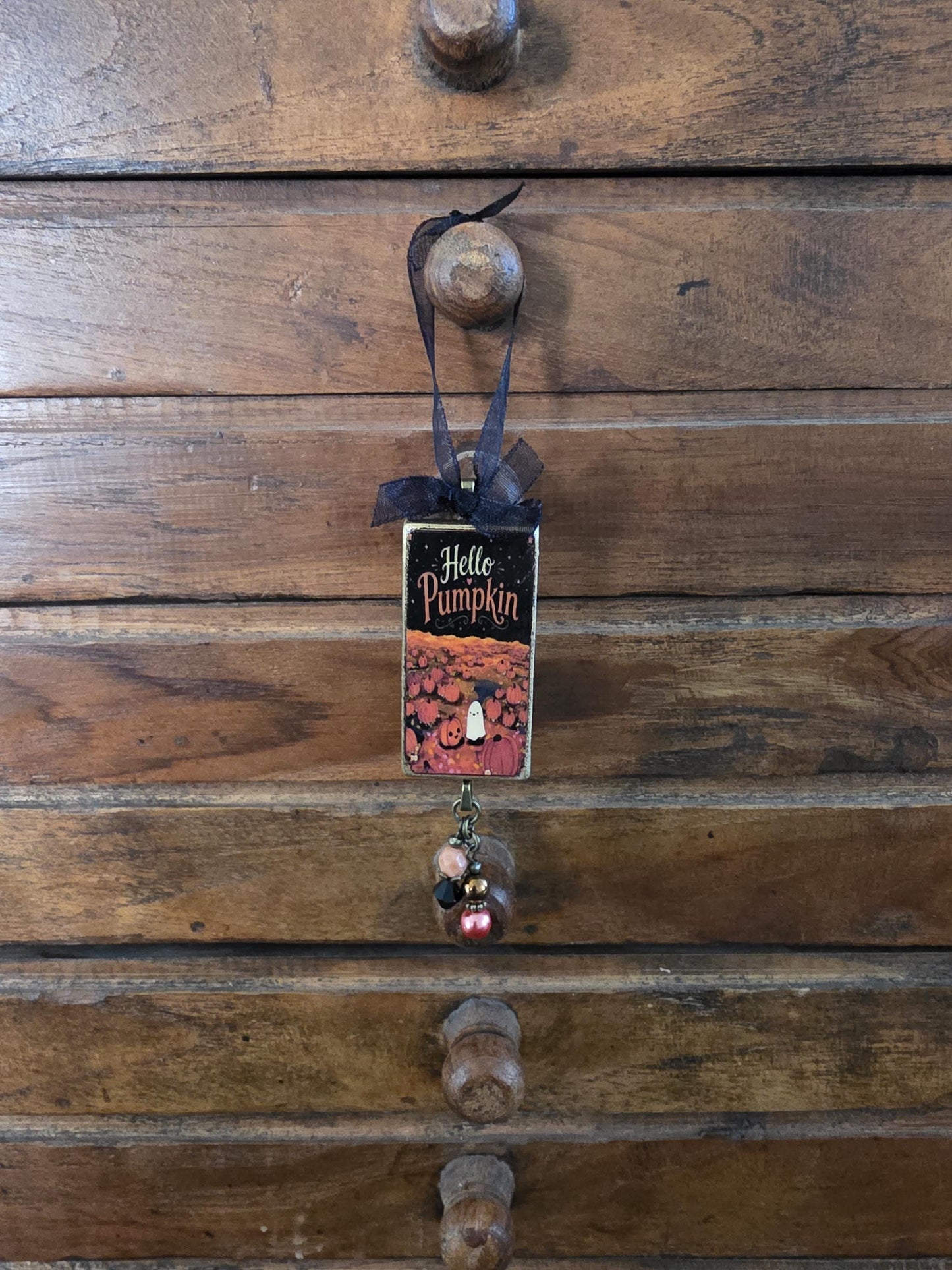 A small wooden drawer with a black ribbon hanging from it, featuring a picture of pumpkins and the text "Hello Pumpkin".