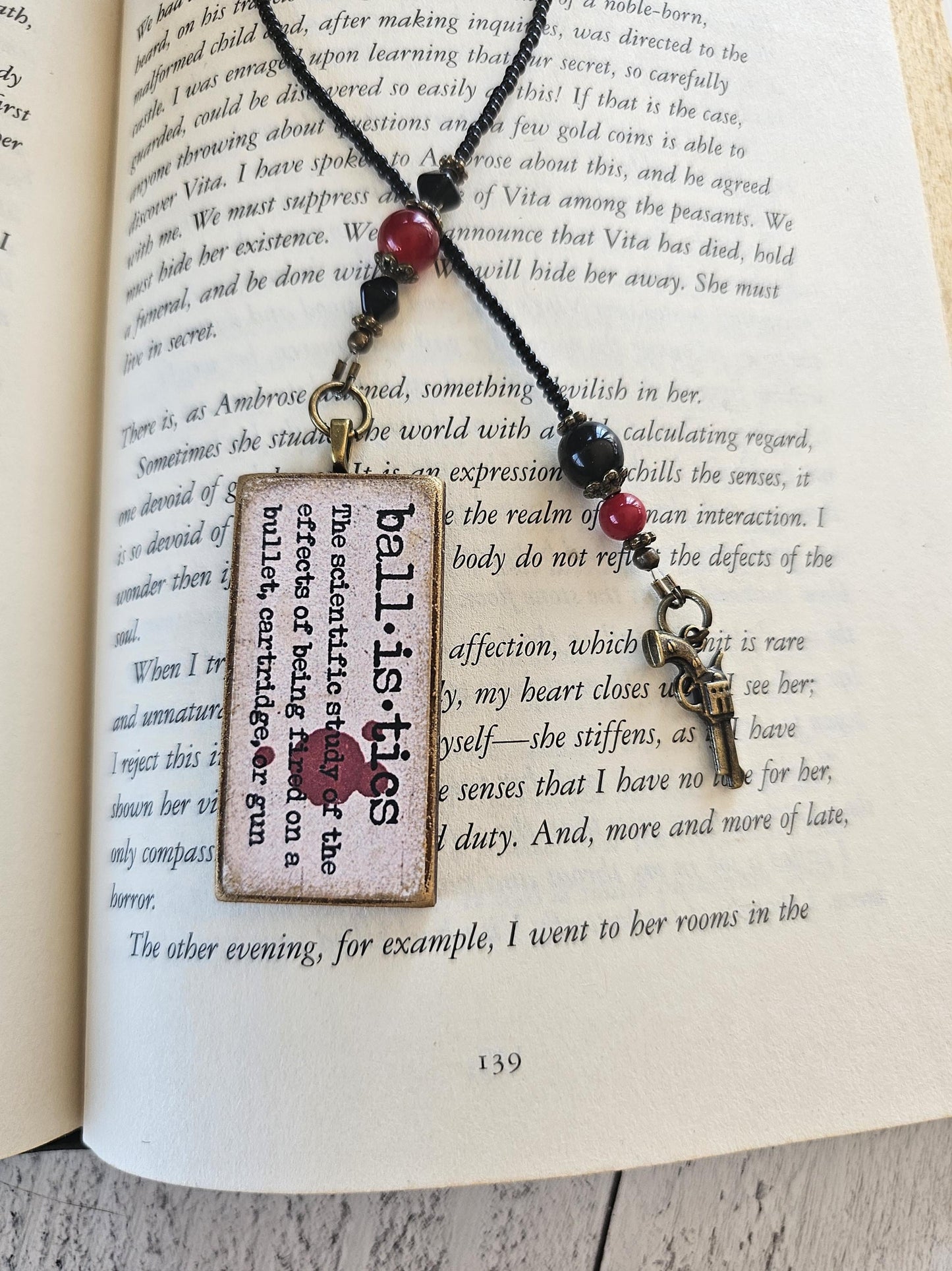 a pair of metal bookmarks with text and beads resting on an open book.