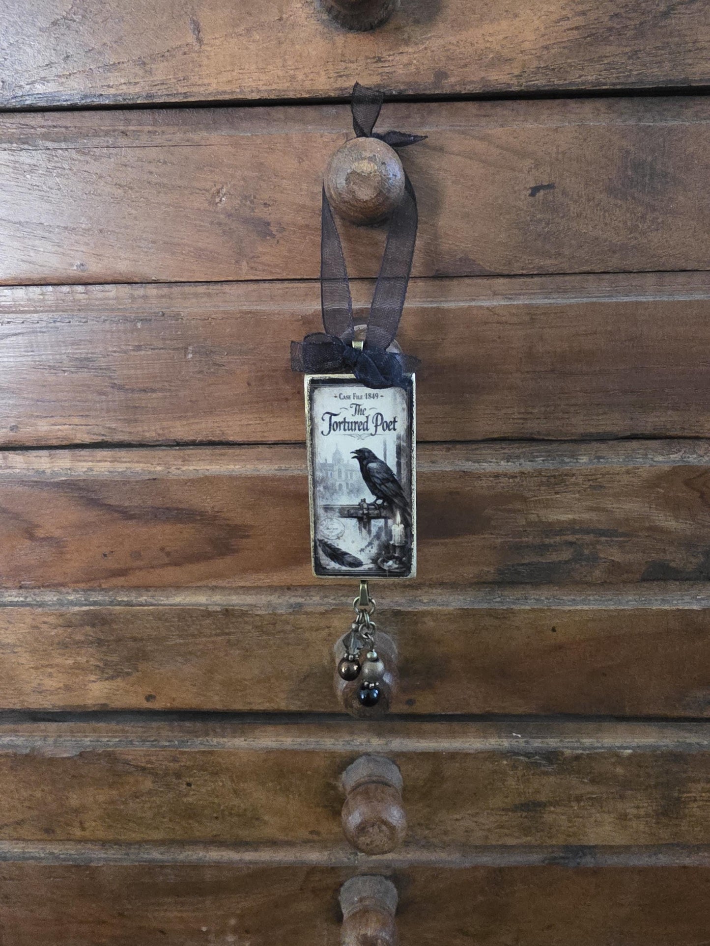 a wooden drawer with a small decorative item hanging from it, which appears to be a book or a card.