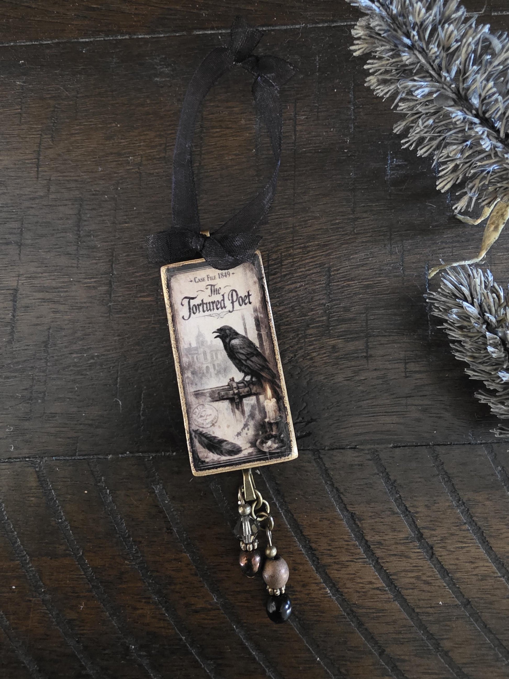a small decorative ornament with a black ribbon and a black and white illustration of a bird perched on a bridge.