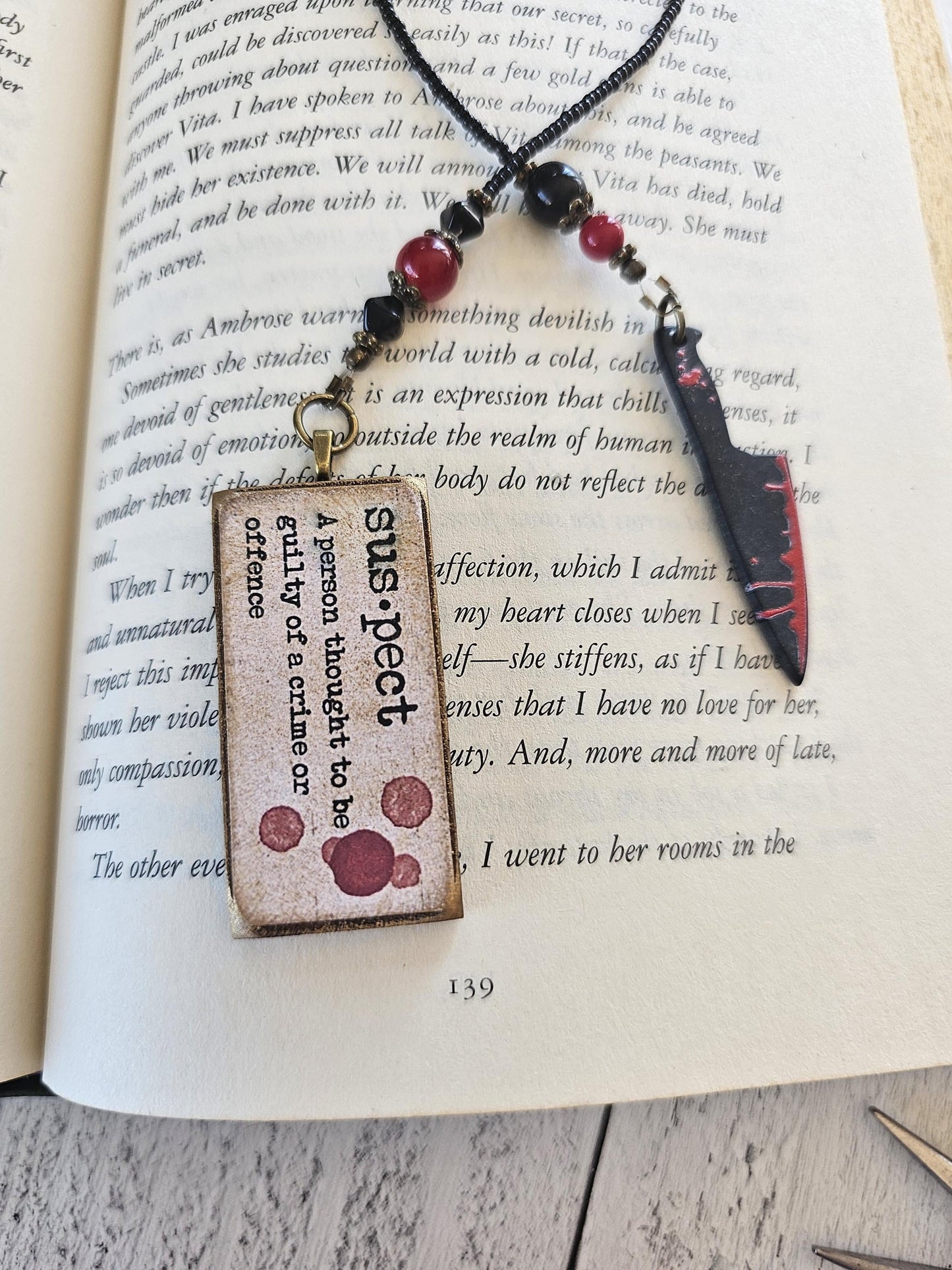 a pendant with a text design hanging from a necklace, resting on top of an open book.